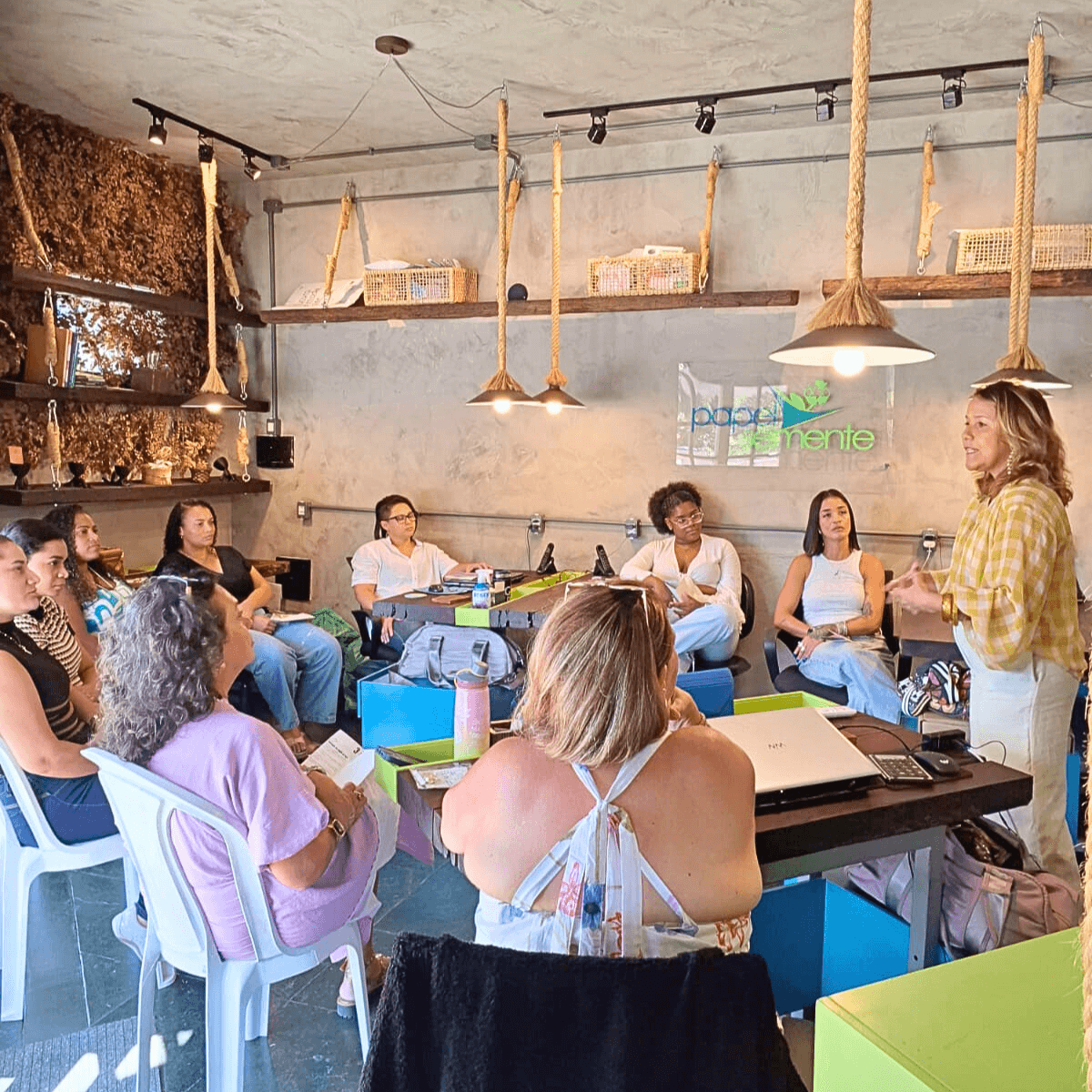 Grupo de mulheres reunidas em volta de uma mesa grande para um workshop ou encontro.
